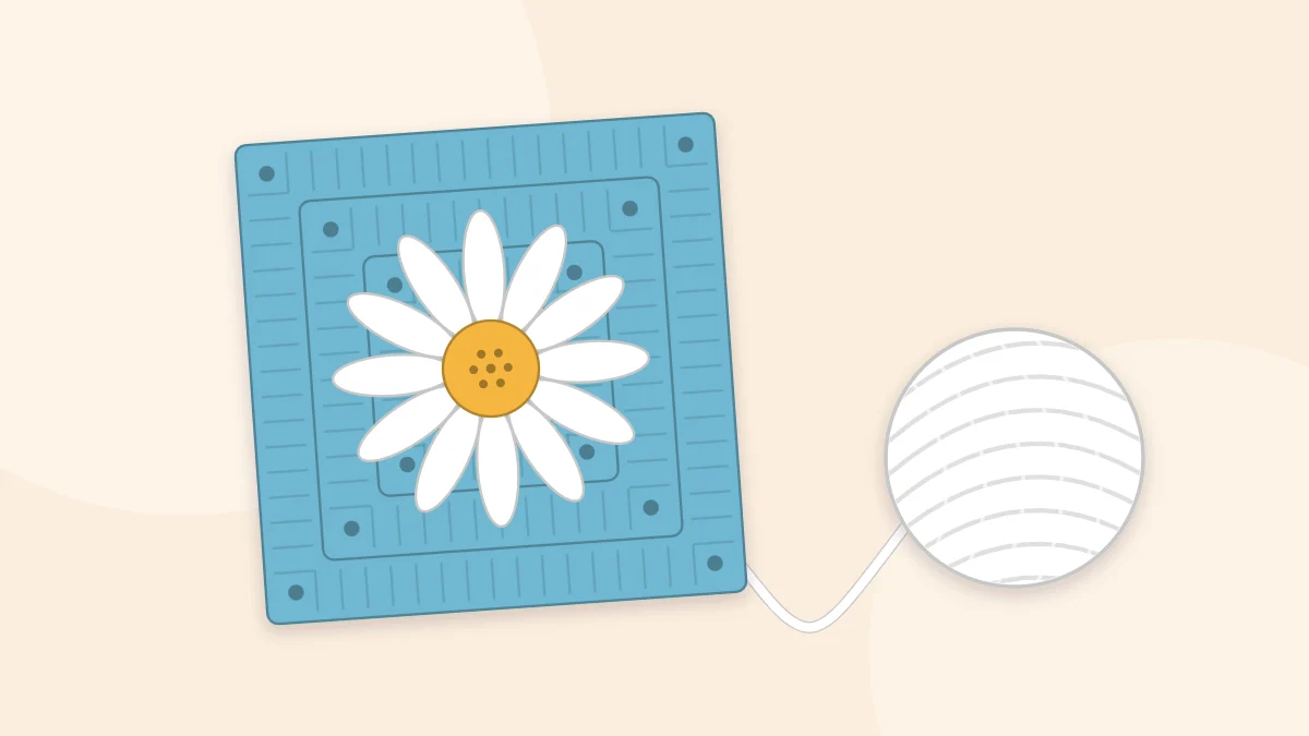 A daisy granny square with a yellow center, white petals and a blue background, with a ball of yarn beside it